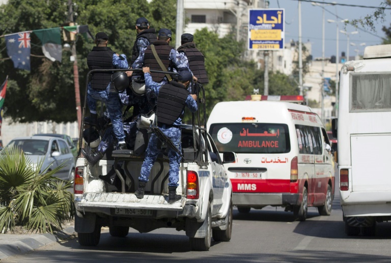 أفراد من الشرطة يرافقون سيارة إسعاف تحمل جثث القتلي AFP